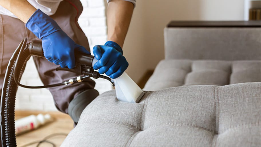 Man professionally cleaning couch - Преимущества химчистки мягкой мебели